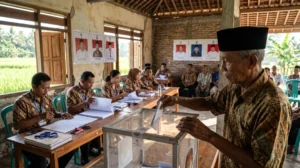 Warga memasukkan surat suara ke kotak transparan saat pilkades serentak di balai desa